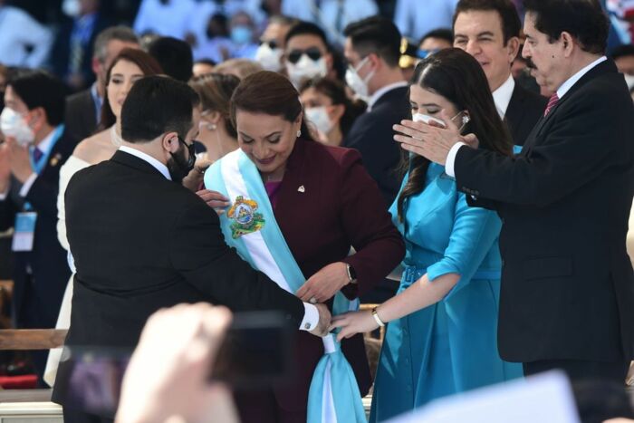 Amtsantritt: Parlamentspräsident Luis Redondo hängt Xiomara Castro die Präsident*innen- Schärpe um. Rechts im Bild: Ihr Ehemann und künftiger Berater, der 2009 durch eine Putsch gestürzte Ex-Präsident Mel Zelaya.