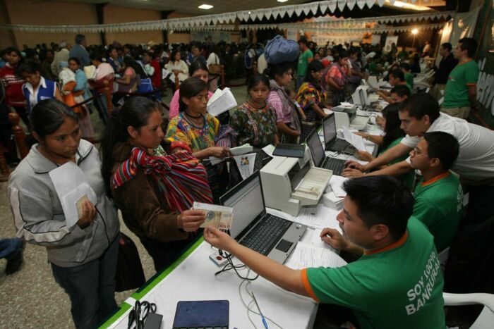 Frauen in San Juan Sacatepequéz (Guatemala) holen ihre Geldsendungen ab. Was damals Regierungspropaganda für die Konditionierung von remesas zugunsten von Gesundheit und Bildung sein sollte, hat sich heute fast vollständig ins private Handy verlagert.